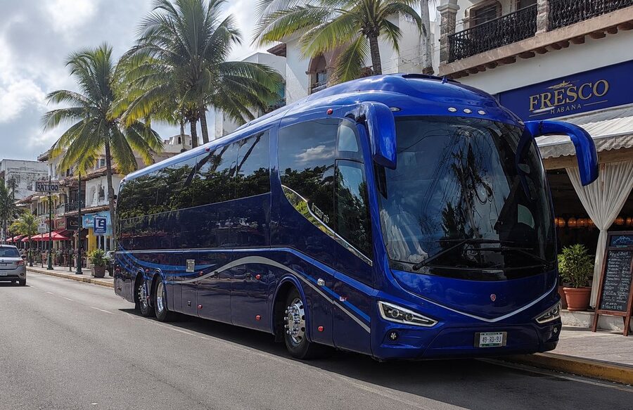 Autobús turístico azul de 48 lugares de zertravel estacionado en una avenida con palmeras