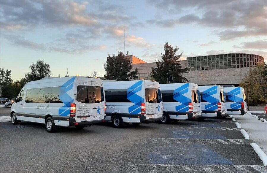 Camionetas Sprinter blancas de 20 lugares de zertravel formadas en el patio de operaciones al atardecer