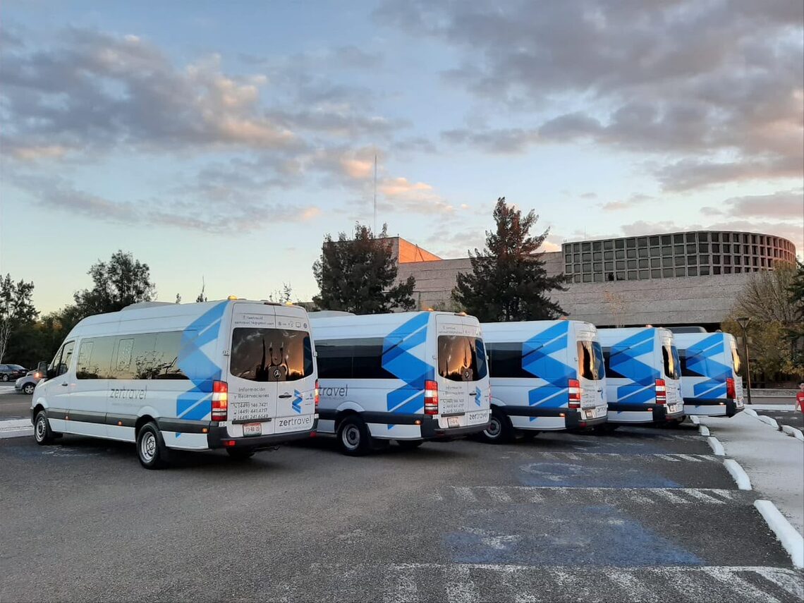 Camionetas Sprinter blancas de 20 lugares de zertravel formadas en el patio al atardecer
